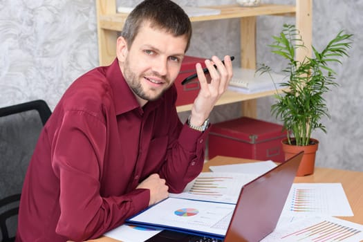 Man in the office listens to voicemail on mobile phone