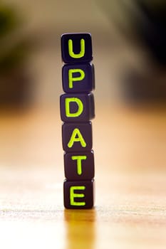 Update, vertical text in black cubes on a wooden table