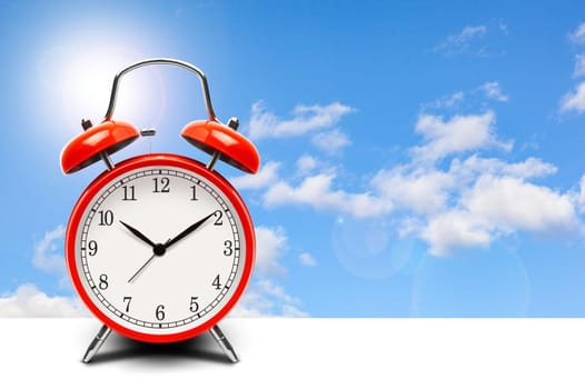 Red alarm clock on blue sky background with copy space. With clippinj path