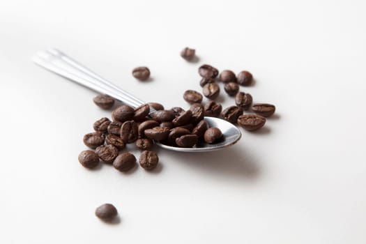 Spoon with coffee beans, macro photo. Isolated on white background