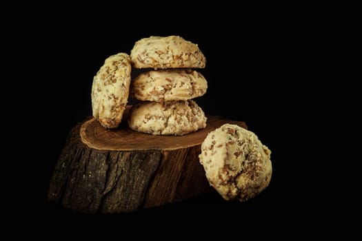 Shortbread with nuts and seeds on a wooden stand on a black background. Сlose up