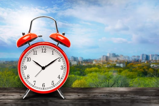 Red alarm clock on city and blue sky background with copy space. With clipping path