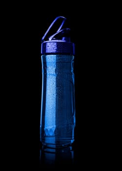 Plastic blue sports bottle is covered with droplets. Isolated on black background. With clipping path