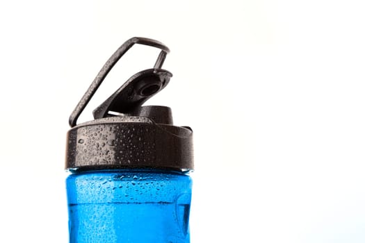 Plastic blue sports bottle is covered with droplets. Isolated on white background.