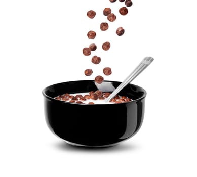 Falling chocolate cereal balls in milk in a black bowl isolated on a white background. Close up with clipping path