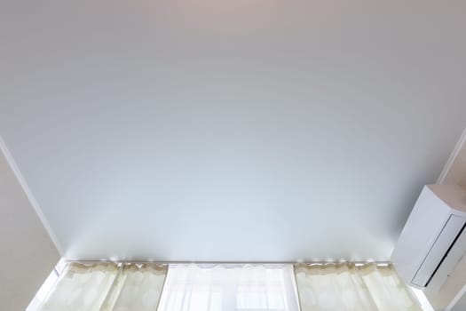 Fragment of a classic stretch ceiling above a window in a room
