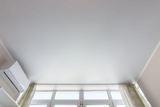 Fragment of the suspended ceiling above the window in the room, next to air conditioning