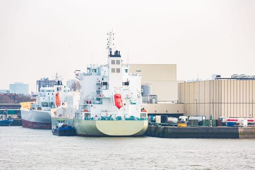 Big Cargo Containers Boat with Goods cargo Stack at the Pier docks port waiting for international sea freight transportation in Rotterdam Port of Netherlands