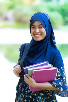 Portrait of good-looking Happy young teenager Muslim islamic asian university girl holding hers books for knowledge and wisdom concept