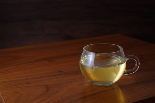 Glass cup of green tea on brown wooden table