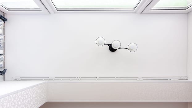 Stretch ceiling with a chandelier in a glazed attic