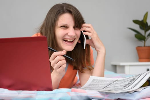 Girl laughs a lot while talking with the employer on the phone and looking for work