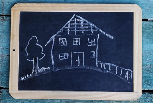 A blackboard with a drawing of a house with garden