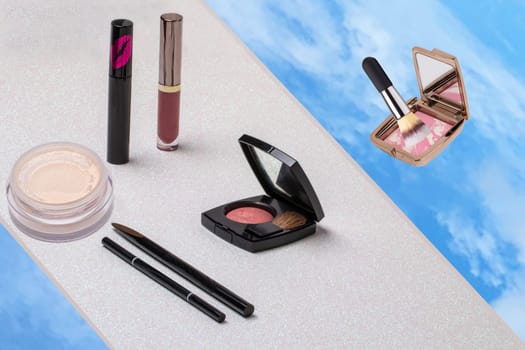Decorative composition of colorful beauty and makeup products and tools such as powder, eyebrow pencil and brushes on a light pink glitter sparkle background with space. Advertising, design, cover and cosmetics background.