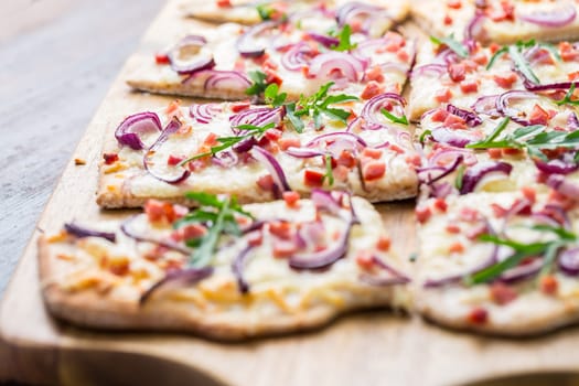 Traditional French dish tarte flambee cream cheese, bacon and onions. Flammkuchen from Alsace region. Flame cake.