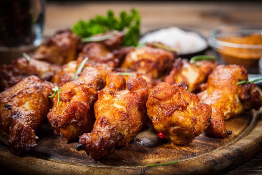 Hot chicken wings with different spices and dips on wooden background