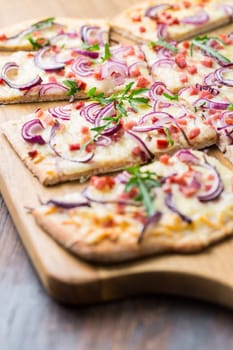 Traditional French dish tarte flambee cream cheese, bacon and onions. Flammkuchen from Alsace region. Flame cake.