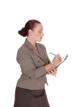 A serious looking business woman writing on her clipboard with a  .blue pen, isolated for white background.