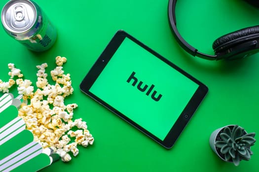 Calgary, Alberta. Canada. June 1 2020. An iPad with the Hulu logo on the screen on a green background with popcorn and headphones