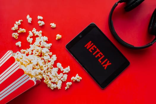 Calgary, Alberta. Canada. June 1 2020. An iPad with the Netflix logo on the screen on a red background with popcorn and headphones