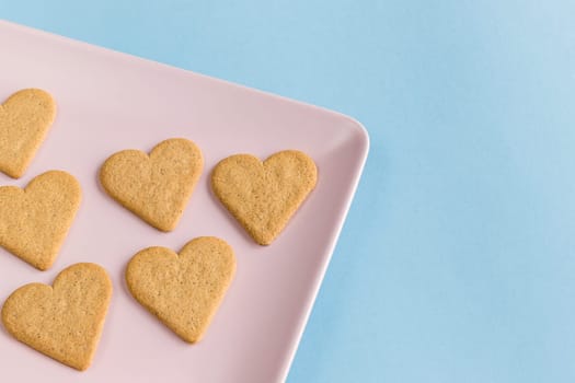 Heart shaped cookies on a pink tray and light blue background. Copy space.