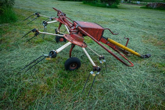 Red rotary rake trailer on a green meadow