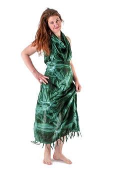 Smiling young woman in dark green dress stands barefoot against white background