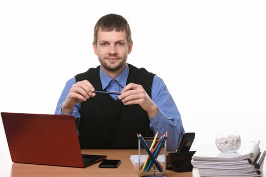 a man sits at an office table and holds a pen on a white background