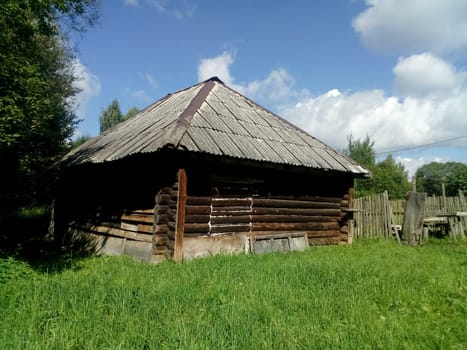 A rustic wooden house and a clearing of green grass in front of it.