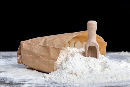 the ingredients for making pasta from durum wheat , white wheat flour in a paper bag with a wooden spoon