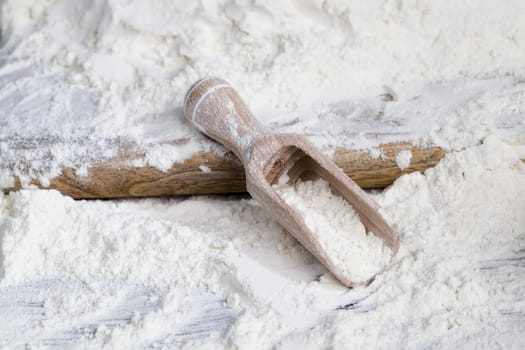a simple wooden spoon with wheat flour while cooking, on a kitchen table in the countryside