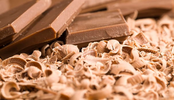 broken crumbs of delicious sweet milk chocolate during the preparation of desserts, details of sweets on the wooden table
