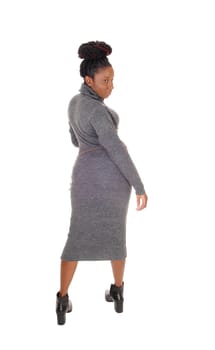 A beautiful young curvy African American female standing in a tight.gray dress, showing her figure, isolated for white background.