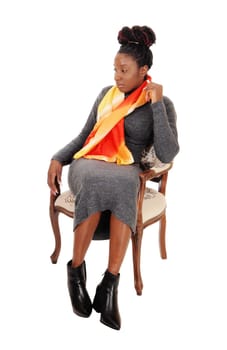 A gorgeous African American woman in a long gray dress sitting in an.old armchair, isolated for white background.