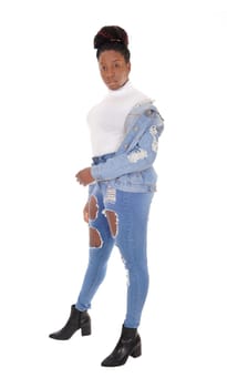 A young African American woman standing in ripped jeans with her.jacket over her shoulder and white top, isolated for white background.
