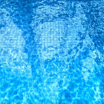 swimming pool with sun glare and optical caustic network on the water