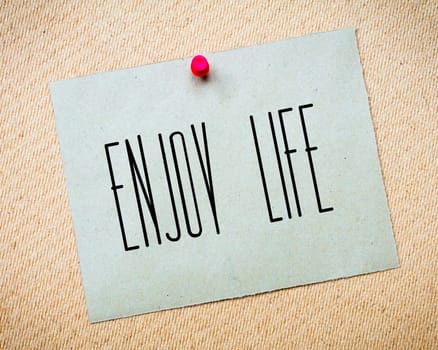 Recycled paper note pinned on cork board.Enjoy Life Message.Happiness Concept Image