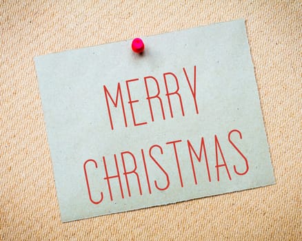 Recycled paper note pinned on cork board.Merry Christmas Message. Concept Image