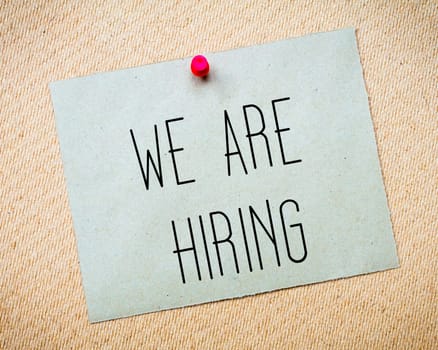 Recycled paper note pinned on cork board.We are hiring Message. Concept Image