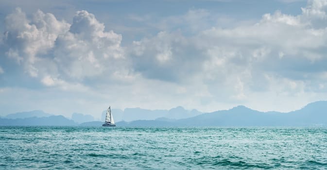 Lone sailboat in the Andaman Sea in Thailand with Krabi coastline in the horizon