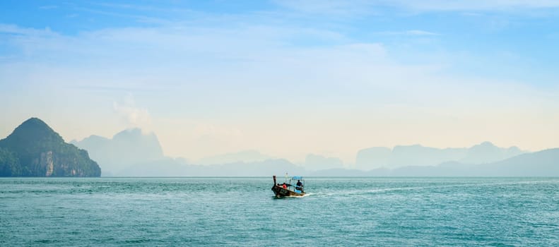 Krabi, Thailand, November 7, 2017: Traditional Thai motor boat in the Andaman Sea with Krabi coastline in the backdrop