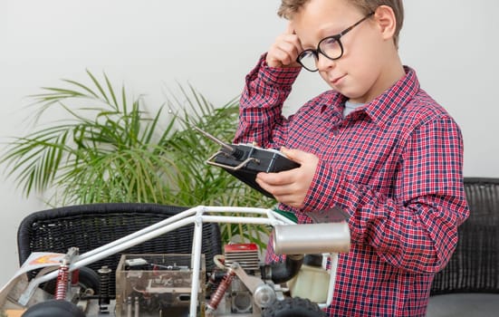 a little boy repairing a model radio-controlled car at home