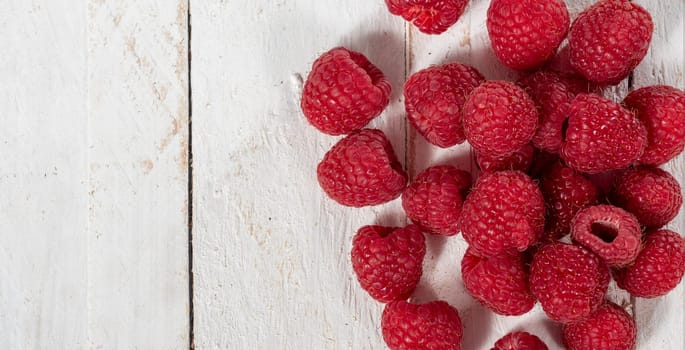 Ripe raspberry on the white wooden background