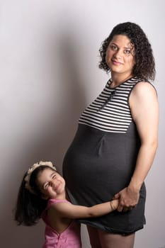 A young beautiful pregnant mother with her two years old daughter, Parenthood and kid’s relationship concept