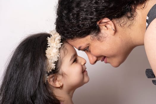 Loving mother and daughter with heads together, happy family or mother's day concept