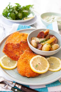Breaded chicken schnitzel with baked potatoes and cucumber salad