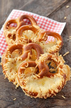 Delicious soft pretzels with cheese on a wooden background