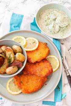 Breaded chicken schnitzel with baked potatoes and cucumber salad