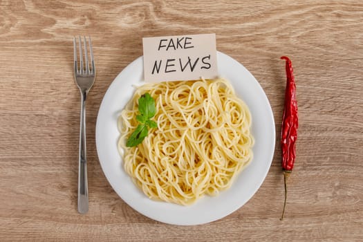 Spaghetti on a plate top view on a wooden background as a concept of fake chili seasoned fake news