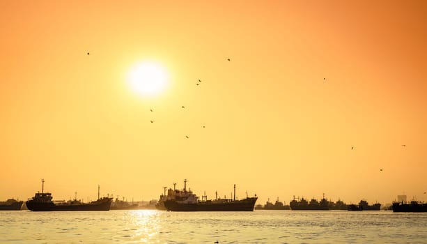 Commercial ships on anchorage in the Karnaphuli River in Bangladesh at sunset